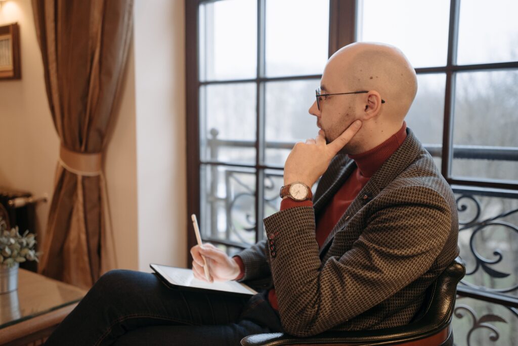 Quando Procurar Terapia? Os Sinais de que É Hora de Buscar Ajuda Side view of a thoughtful psychotherapist in a cozy office, holding a tablet.