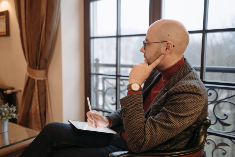 Side view of a thoughtful psychotherapist in a cozy office, holding a tablet.