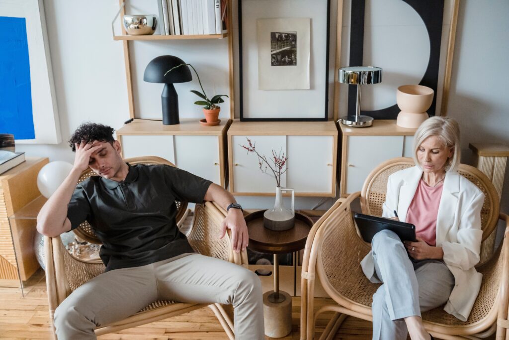 TCC Funciona para Estresse no Trabalho? Entenda a Abordagem Científica A stressed man and woman therapist in a modern consultation room.